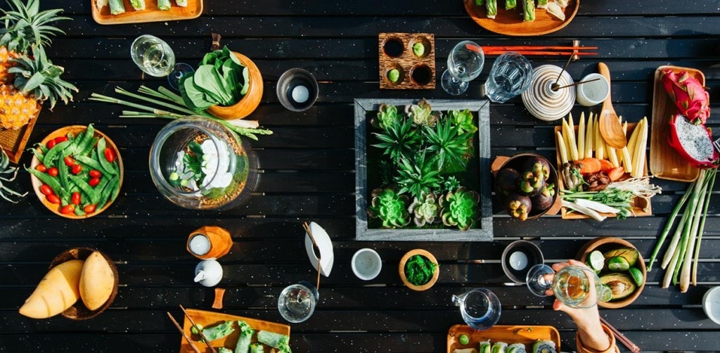A counter top filled with Asian cuisine from rice paper rolls to sushi and fresh vegetables.