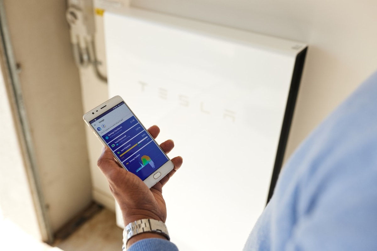 Close shot of Kartik holding mobile showing app