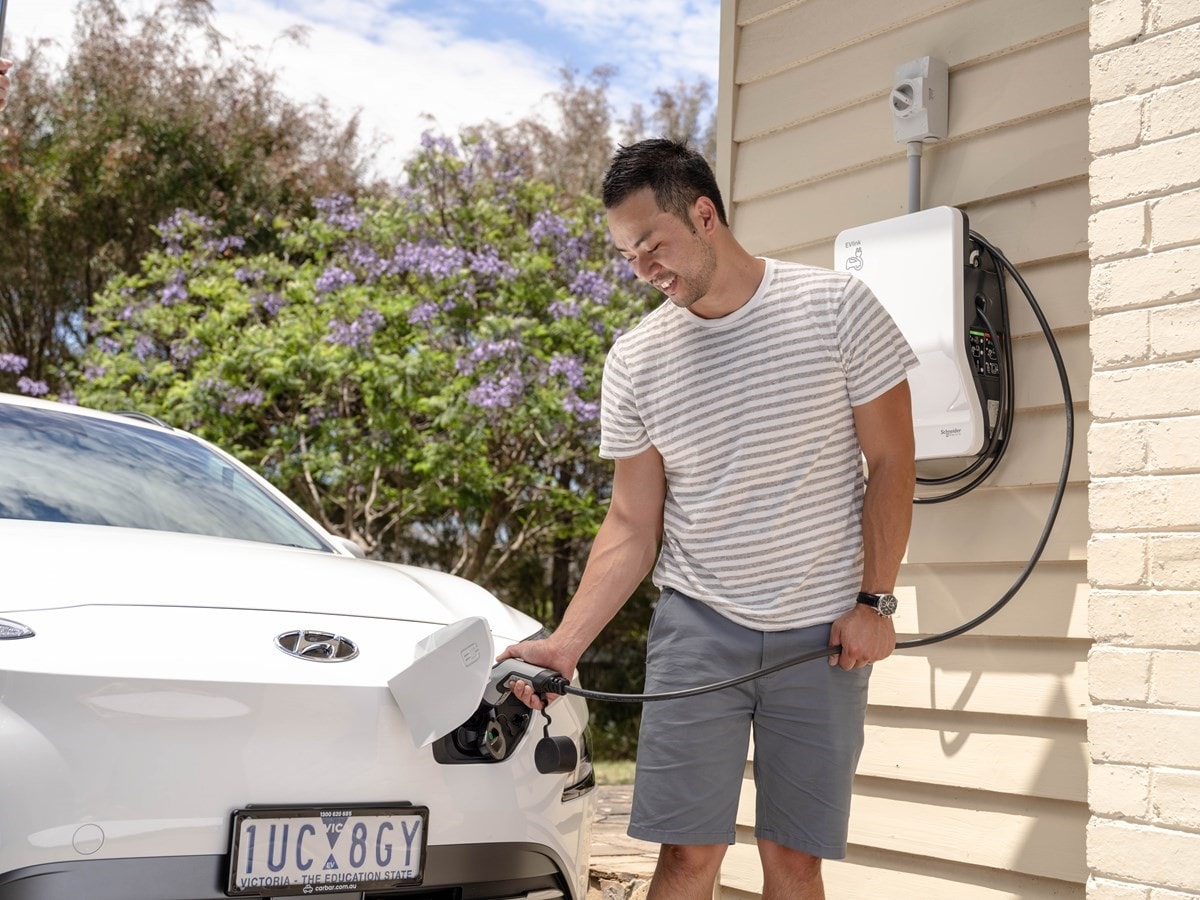 Man standing up outside charging his white EV