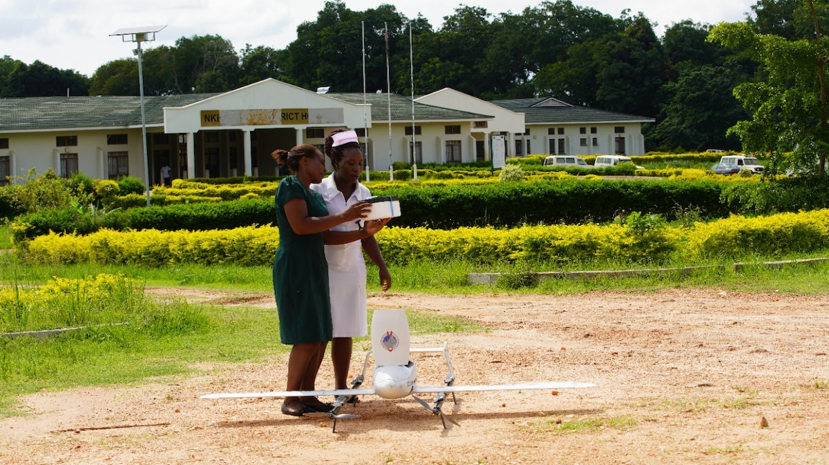 Two medical staff standing next to grounded Swoop Aero drone