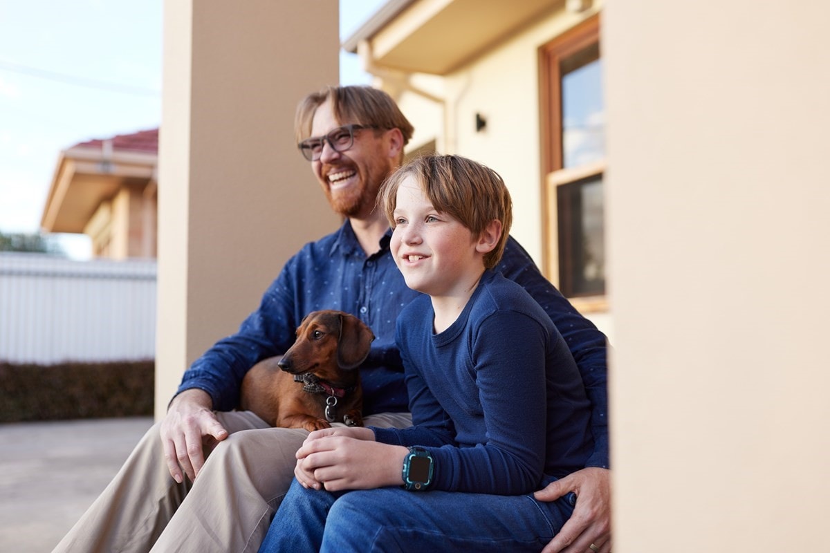 Happy father and son sitting out the front of their house