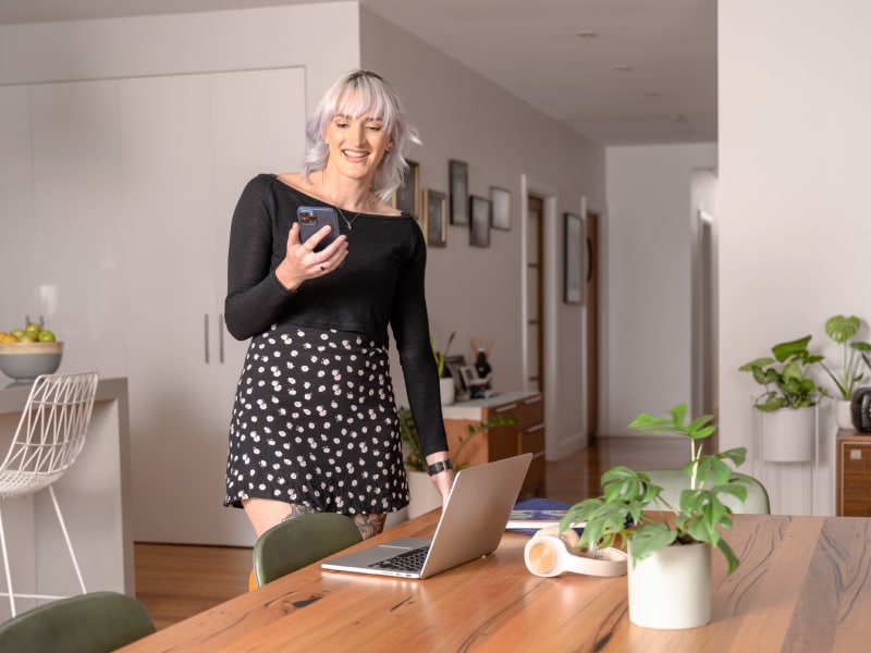 Woman standing next to a desk while she looks at a phone