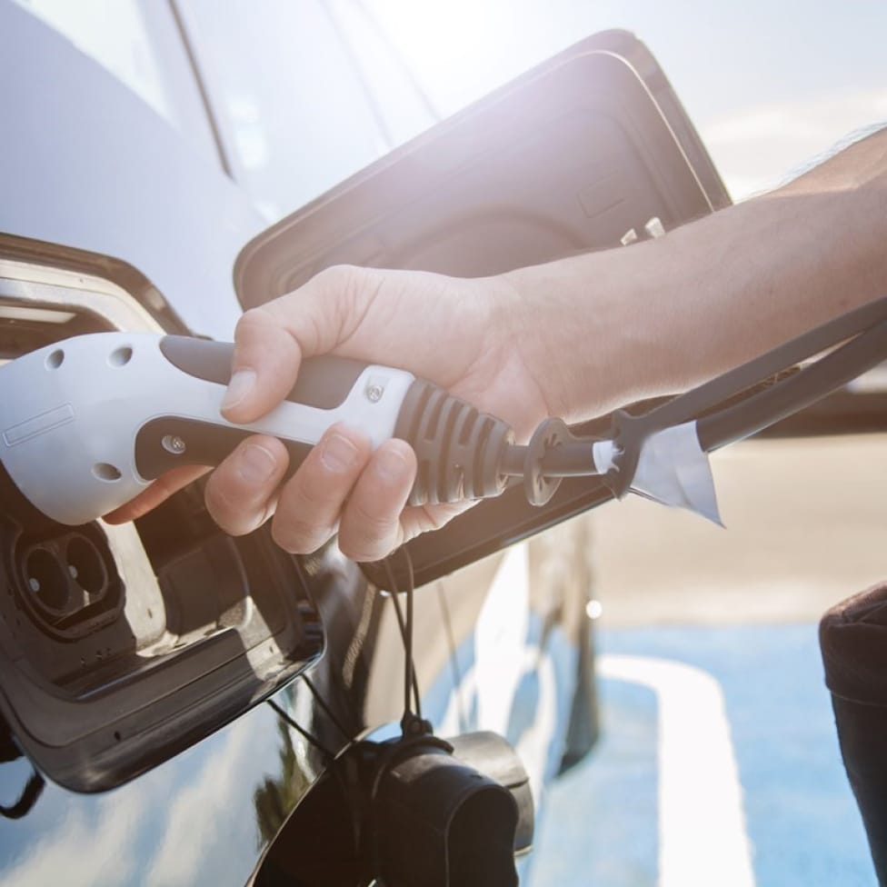 Hand plugging in a charger to an electric vehicle.