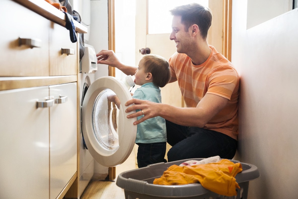 Father and toddler using washing machine