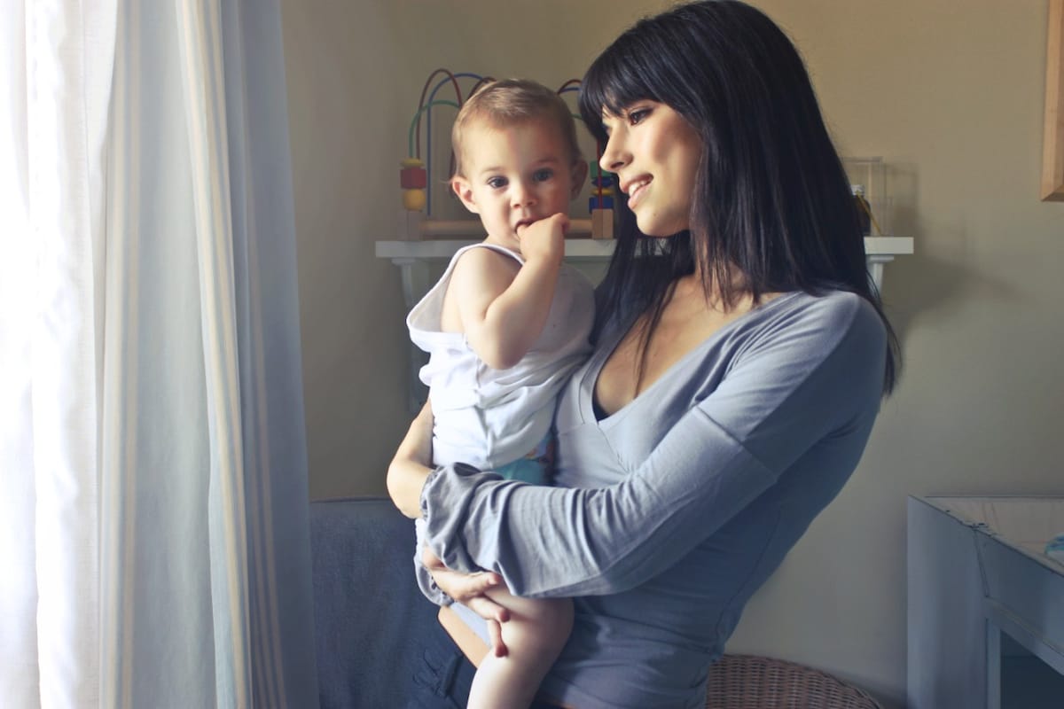 A mother and her baby looking out the window in the nursery