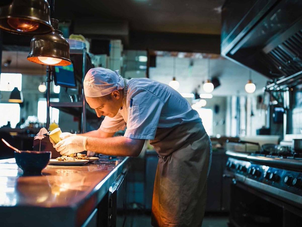 Chef in a commercial kitchen plating up food