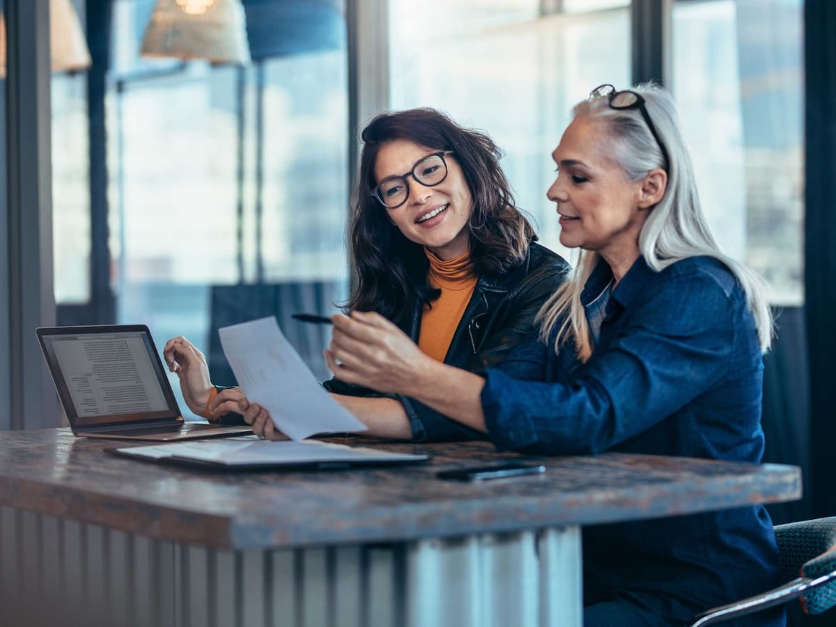 Two women analysing a document seated at an office workstation
